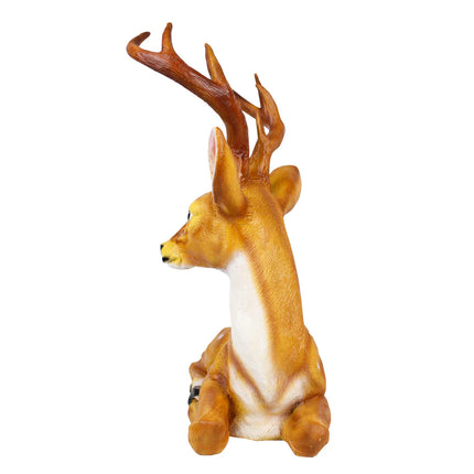 Outdoor deer sculpture with antlers resting on grass in a beautiful garden setting