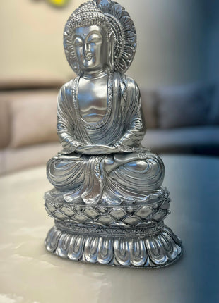 Silver Buddha statue with ornamental halo-style backdrop