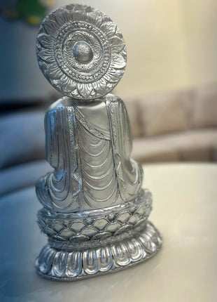 Silver Buddha statue with ornamental halo-style backdrop