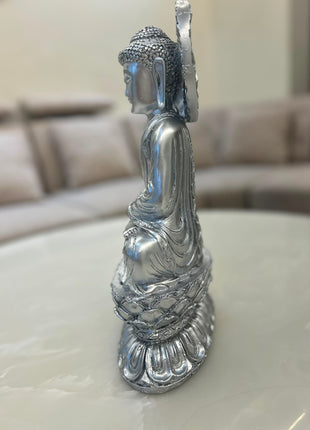 Silver Buddha statue with ornamental halo-style backdrop